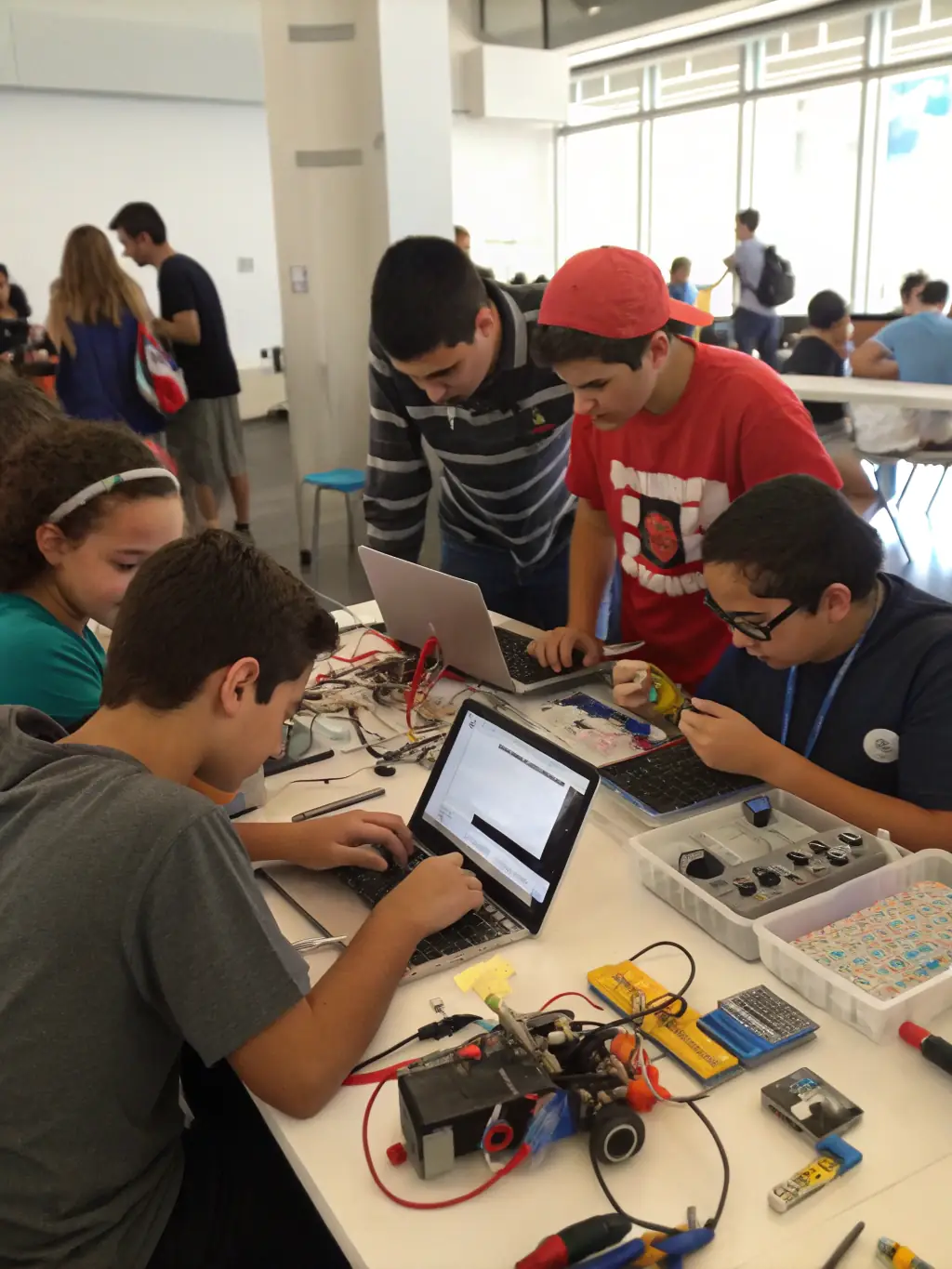 A diverse group of students collaborating on a robotics project, with one student holding a small robot and others looking on with interest, in a modern classroom at Bizzern Engineering.